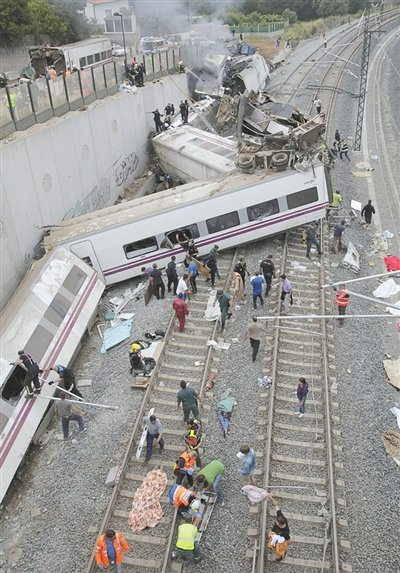 24日，救援人員在西班牙列車脫軌現(xiàn)場。一節(jié)車廂被強大的慣性拋上鐵道邊的高臺。