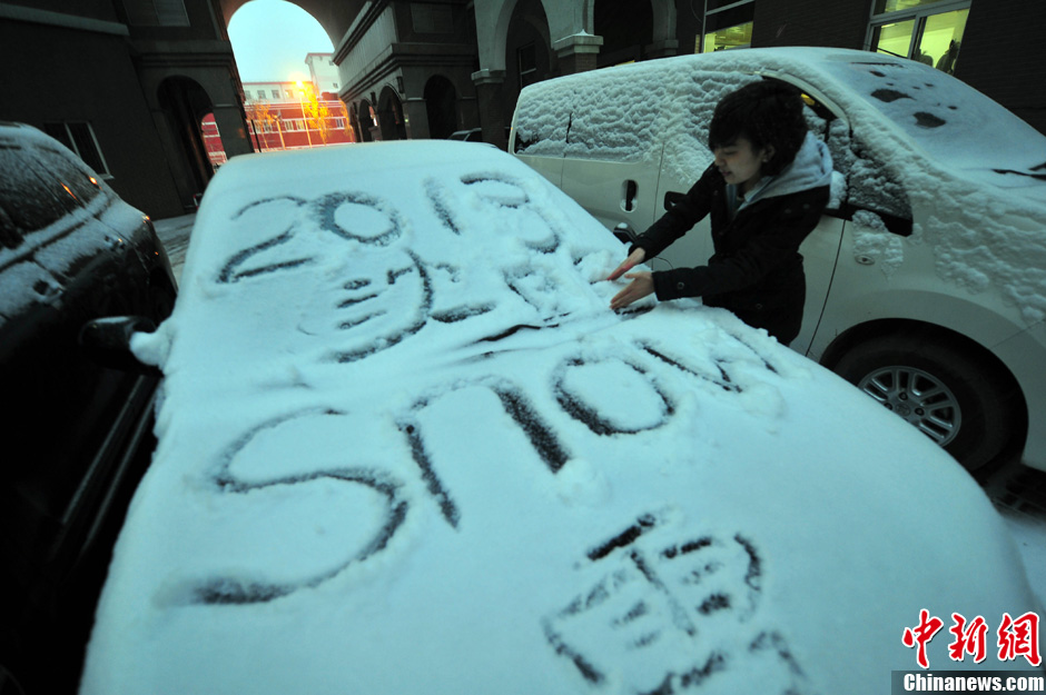 11月18日，行人在車(chē)輛的積雪上涂鴉。