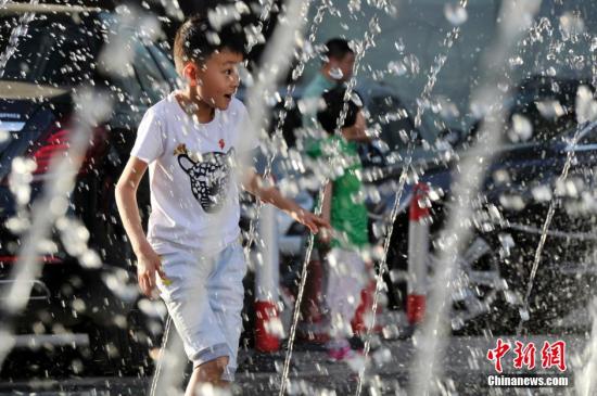 山西太原最高溫36℃,兒童在噴泉周圍戲水消暑。