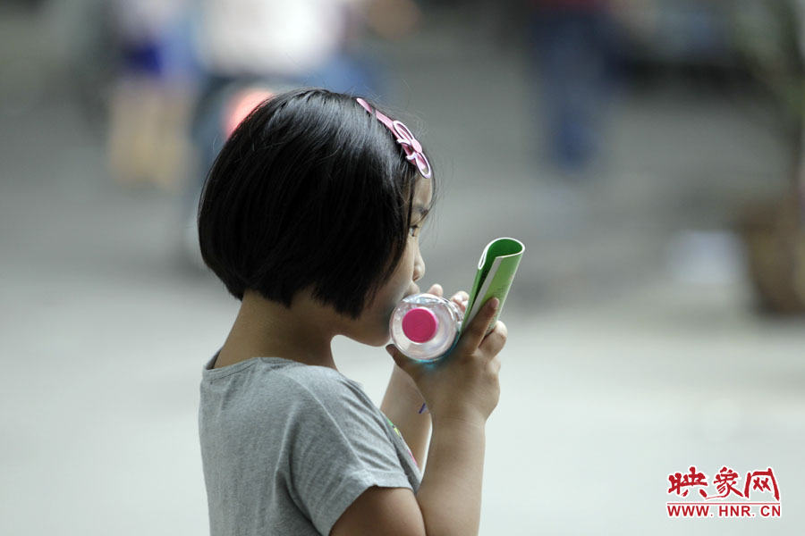 6月7日，鄭州回中考點(diǎn)，一名孩子拿著一瓶礦泉水，等待哥哥走出考場