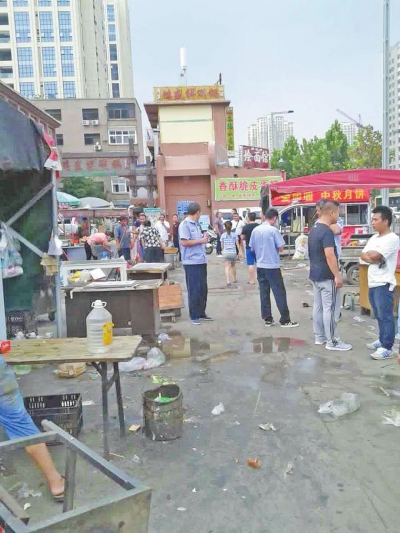 昨天，執(zhí)法人員在京廣路長江路口整治“僵尸圍擋”及圍擋內(nèi)的攤販。