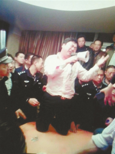 　4月19日，泰州市濱江工業(yè)園區(qū)管委會(huì)招待中心，一男子跪在酒桌上喊話求饒。李根 攝