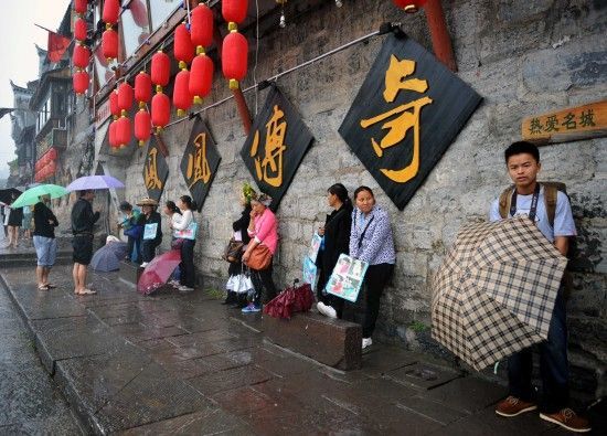 　4月29日上午11時(shí)20分，一些游客和古城當(dāng)?shù)氐木用穸阍谝粋€(gè)酒吧的屋檐下避雨。這些當(dāng)?shù)鼐用褚詾橛慰团恼罩\生，一場(chǎng)降雨讓他們的生意更加清淡。