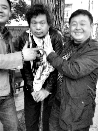 兩名接訪(fǎng)人員與患有癌癥的訪(fǎng)民段新德合影時(shí)，面帶笑容擺出勝利的手勢(shì)。