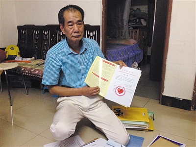 翻出一家網(wǎng)站贈予的“中國好人”證書，區(qū)少坤單膝跪在地上，“你看，我是中國好人啊?！?范春旭 攝