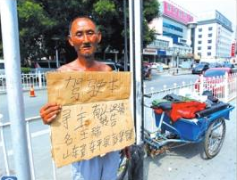 老人舉著牌子在路邊等候失主。京華時(shí)報(bào)記者譚青攝