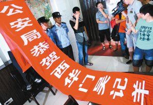 面對(duì)警方收繳的條幅，老板楊某也不好意思地用手遮擋臉