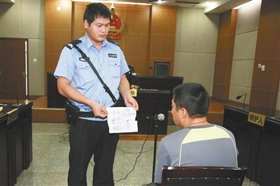 昨日庭審中，法警向趙某出示其扎完車胎后所留辱罵公司的紙條。通訊員 李秀文 攝