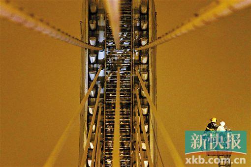 截至今日零時(shí)，男子仍未有下橋舉動(dòng)。圖為公安和消防人員乘消防云梯在高空上和男子交談。