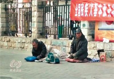 工人體育場北路，兩位乞討者路邊乞討，并輪流扮成“病人”（躺地者）。 央視截圖