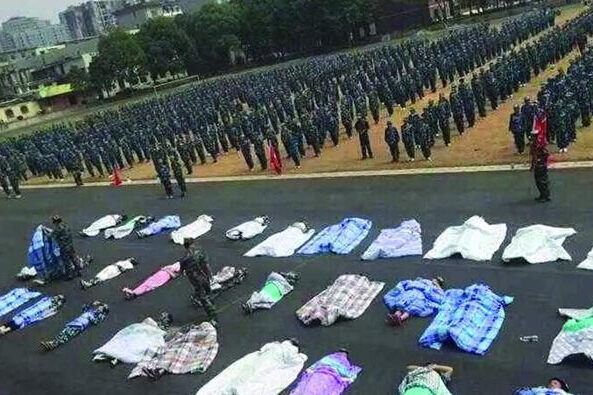 20多名女生躺在瀝青跑道上，身上嚴嚴實實地裹著棉被，接受太陽的照曬。