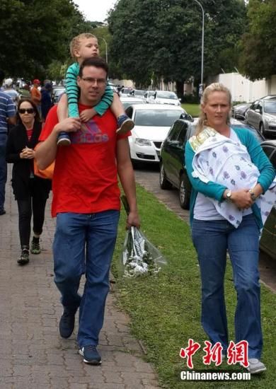 圖為一個(gè)白人家庭，由父母帶著孩子到曼德拉家門外悼念。中新社發(fā) 宋方燦 攝