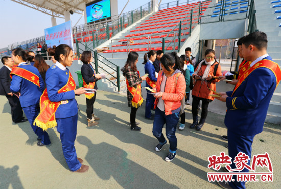 活動現(xiàn)場工作人員給同學們發(fā)放宣傳冊、環(huán)保袋。