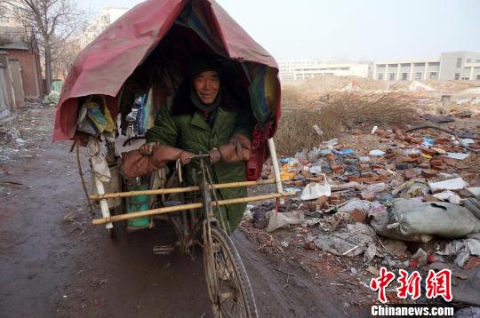 圖為老人走出窩棚，推著三輪車準(zhǔn)備出去撿拾廢品。周小云 攝