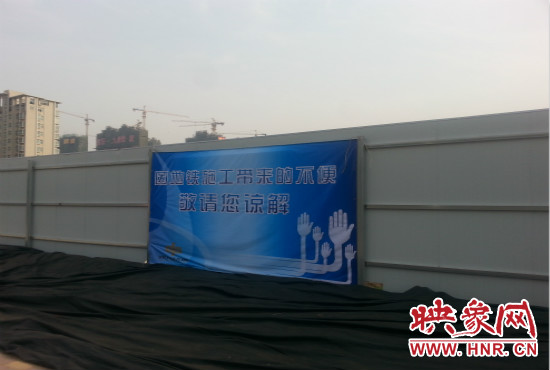 道路南側(cè)圍起了白色的圍擋，墻上標(biāo)示著“因地鐵施工帶來(lái)的不便敬請(qǐng)您諒解”的提示牌。