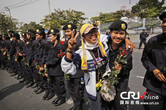 2013年12月03日,曼谷總理府與曼谷警署允許反政府示威民眾進(jìn)入,雙方進(jìn)入暫時(shí)“停戰(zhàn)”狀態(tài)迎接泰王生日。曼谷警察總署,女警們手持鮮花送給反政府示威民眾。圖片來(lái)源:Manish Swarup/東方IC