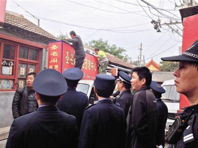 昨日下午,東城區(qū)工商、城管、公安等部門,對雍和宮附近的預(yù)測中心進行清理整頓,站在車頂?shù)膬擅と苏鸪患摇邦A(yù)測中心”的招牌。因雍和宮、白云觀等文化景點外聚集大量算命先生,被媒體稱為“算命一條街”。本版攝影/新京報記者 李寧 攝