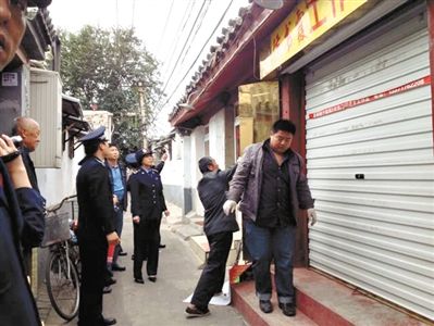 執(zhí)法人員拆除胡同里一家店面未經(jīng)審批的招牌。