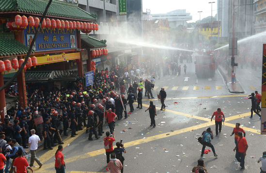 圖為鎮(zhèn)暴警察在吉隆坡的華人聚居地茨廠(chǎng)街向紅衣人噴射水柱