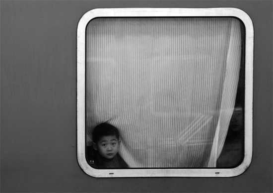 一個孩子把頭伸向窗外，他想再看送別的親人一眼