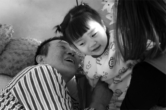 病床前李剛父女倆說著“悄悄話”，幸福的氣氛洋溢在病房中