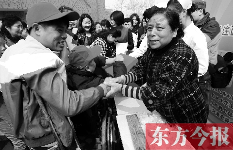 昨日，鄭大四附院的大樓前，“面人鄭”鄭玉芬（右）向前來捐款的殘疾人表示感謝