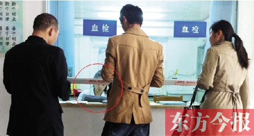 昨日，鄭州市二七區(qū)疾控中心辦證大廳，血檢窗口內(nèi)一名女工作人員，邊接受辦證者咨詢邊看報(bào)紙