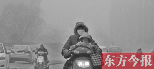 12月8日，鄭州市未來路上，一位市民帶著孩子在霧中騎行