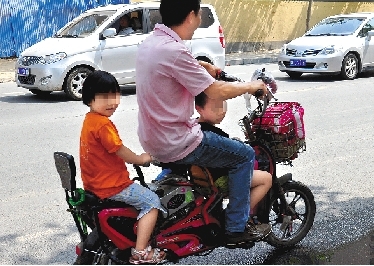 周先生騎著一輛低矮的電動(dòng)車帶著一對(duì)兒女，很不安全。
