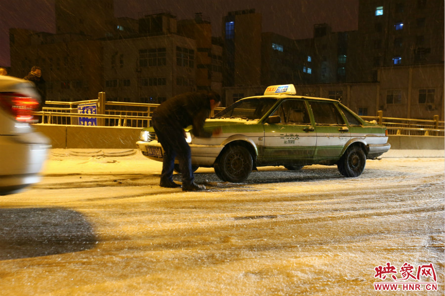 一位出租車(chē)司機(jī)在車(chē)輪前灑上雪，希望能增加輪胎的摩擦力。