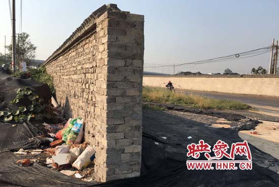 一墻之隔，一邊是道路，一邊是垃圾和荒草，市民質(zhì)疑其為遮羞墻。