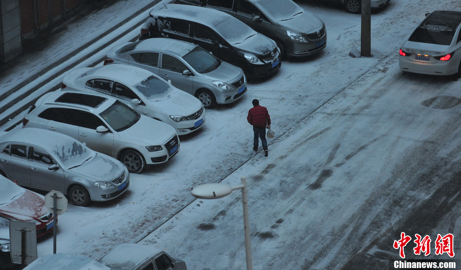 11月18日，行人在沈陽街頭的積雪中穿行。