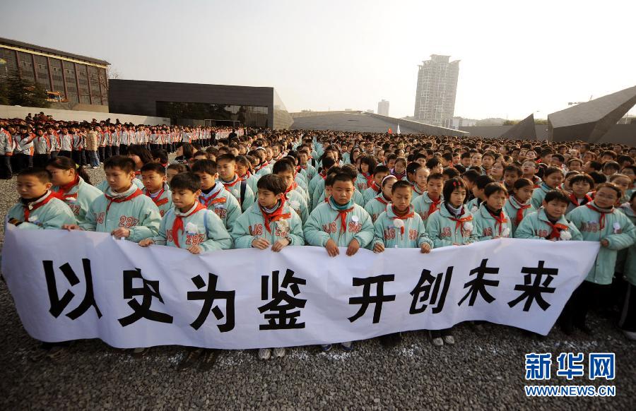 ，南京市小學(xué)生代表手持“以史為鑒 開創(chuàng)未來”的橫幅在南京大屠殺遇難同胞紀(jì)念館集會廣場參加悼念儀式?！? width=