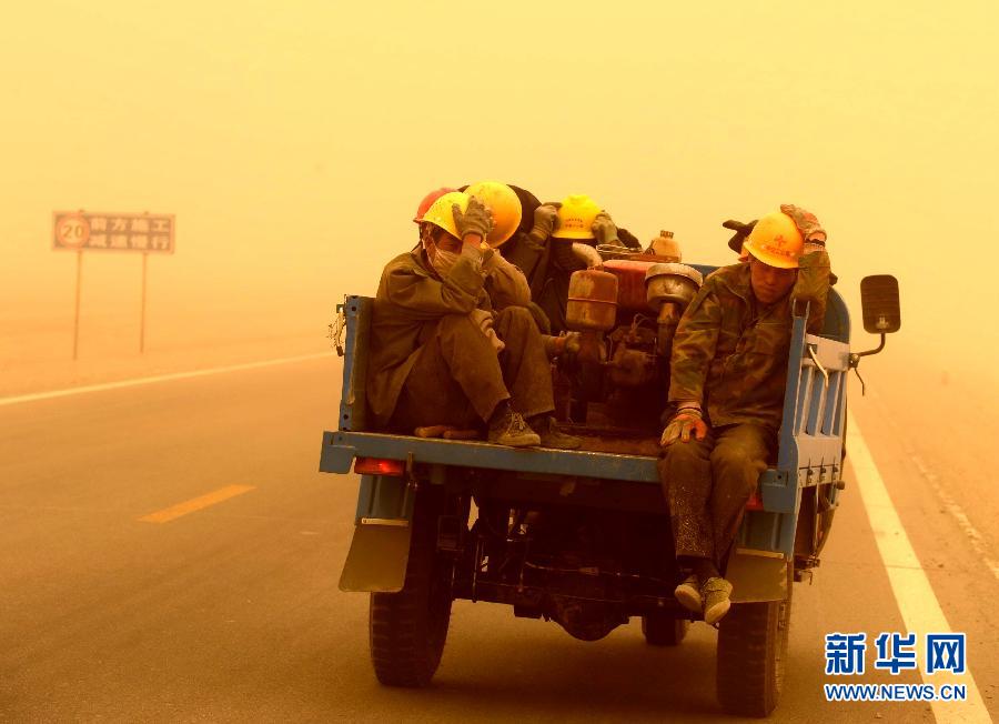 4月23日，一輛拉載公路施工人員的三輪車在沙塵暴中行駛在酒泉市瓜州縣城郊的公路上。
