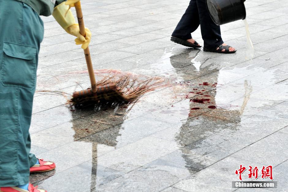 圖為環(huán)衛(wèi)工人在清理案發(fā)地點(diǎn)的血跡。