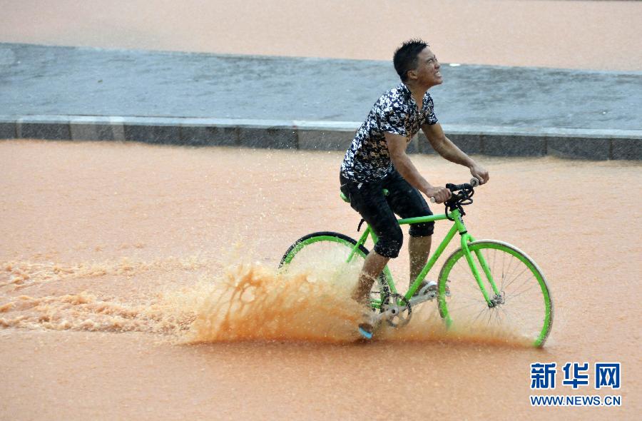 5月11日，一名行人在深圳街頭冒雨騎行。