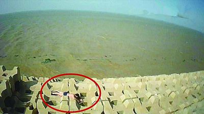 孫正龍游上岸，趴在海邊精疲力盡。