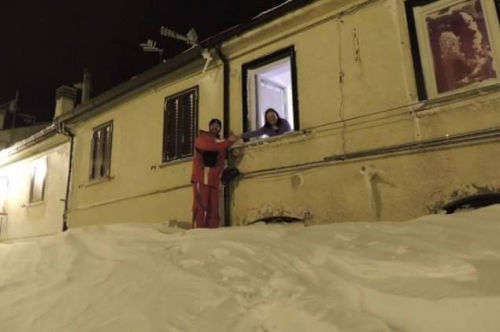 一個居民站在積雪上，可以與一名二樓鄰居在窗口握手。（來源：意大利氣象局）