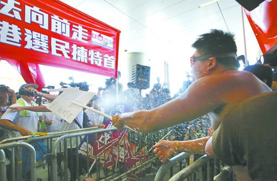 17日，在香港立法會外，一名反對政改的男子向支持派人群投擲標(biāo)牌。