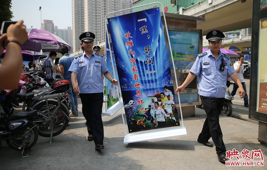 7月2日上午，鄭州市紫荊山地鐵站出入口，執(zhí)法人員抬著寫有勸導(dǎo)語的宣傳板，前往占道經(jīng)營攤位“圍觀執(zhí)法”
