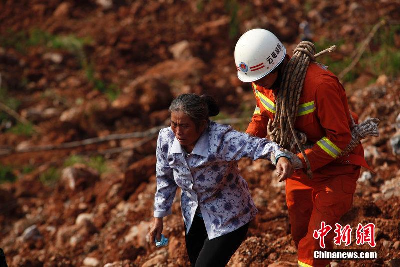 一位消防戰(zhàn)士將一位失去親人的老人扶離滑坡點。