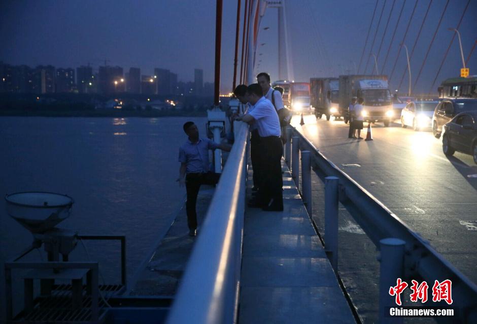 圖為武漢警方談判專家正在與翻爬至大橋外側(cè)護欄的劫持者談判。