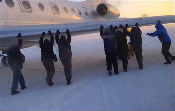 　伊加爾市一架客機起飛前被凍在了跑道上。飛機上的乘客不得不下來推飛機。