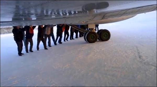 　伊加爾市一架客機起飛前被凍在了跑道上。飛機上的乘客不得不下來推飛機。
