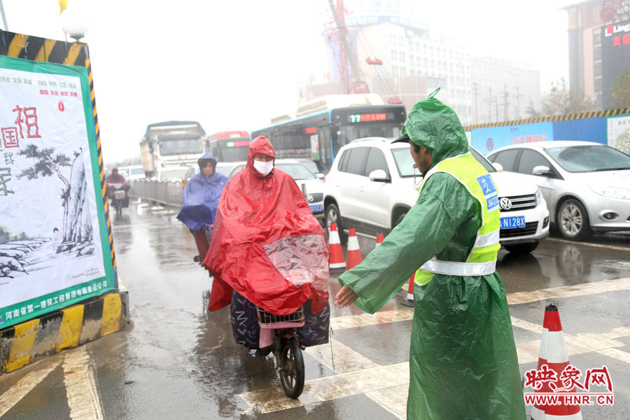 交通協(xié)管員下雨天堅守崗位，疏導交通。
