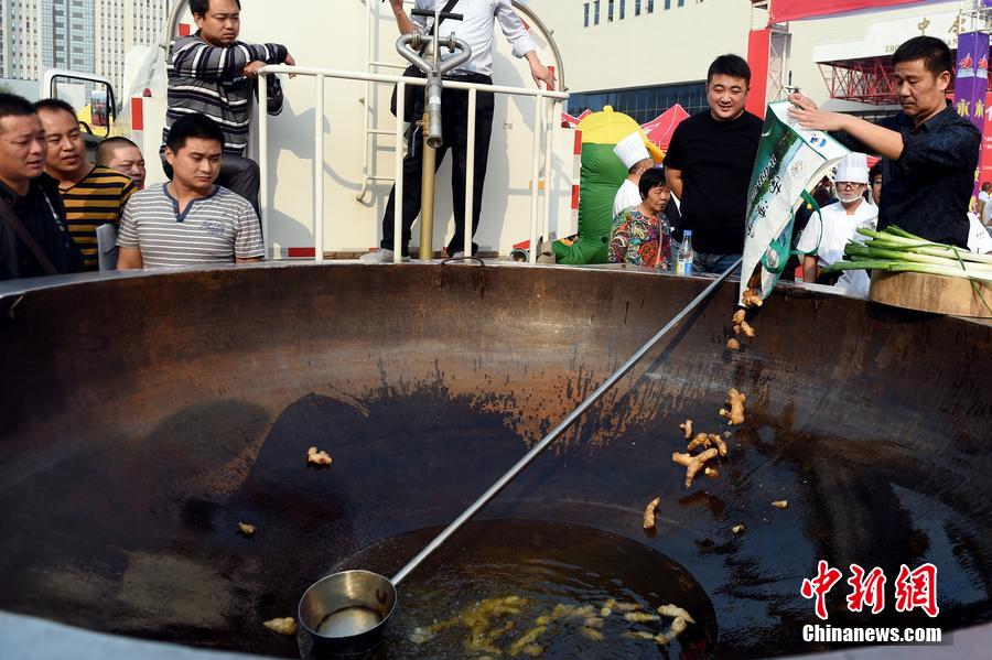 工作人員向大鍋內(nèi)加入油和姜等烹飪調(diào)料。 圖片來源：CFP視覺中國