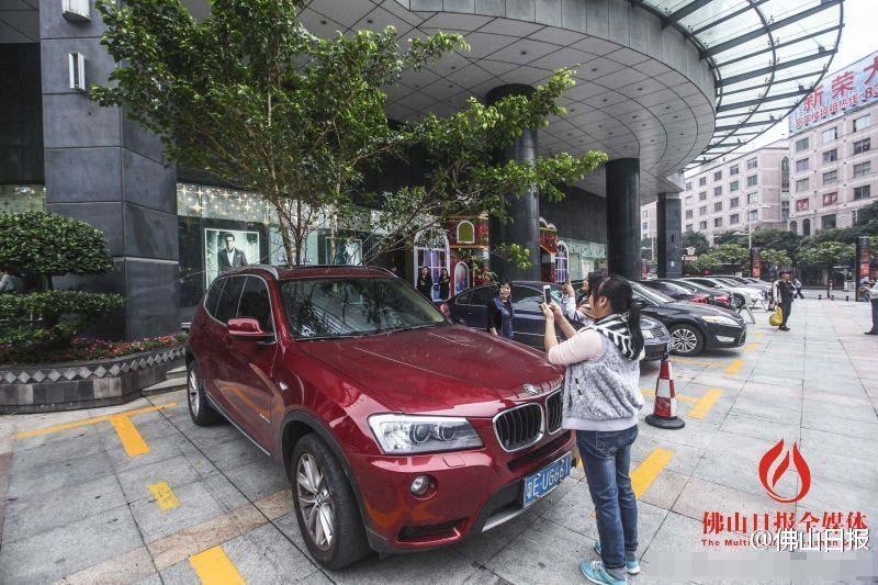 一輛停在停車位上的寶馬轎車，被墜落的樹枝砸中，樹枝徑直插入車內(nèi)，現(xiàn)場引發(fā)不少市民圍觀拍照。