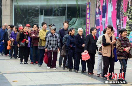 圖為10月28日，在江西九江市一家羊絨皮草服裝服飾博覽會現(xiàn)場，老人們正在頂著寒風排隊等待領取10元代金劵。