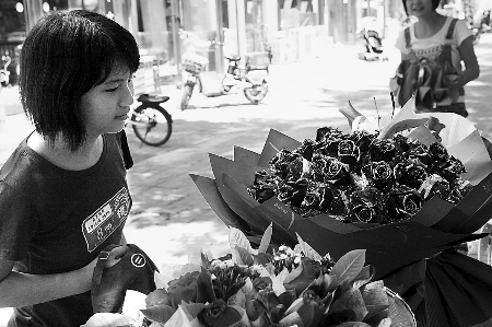 鄭州市農(nóng)業(yè)路一家花店擺放的玫瑰花吸引著一位過往女孩。